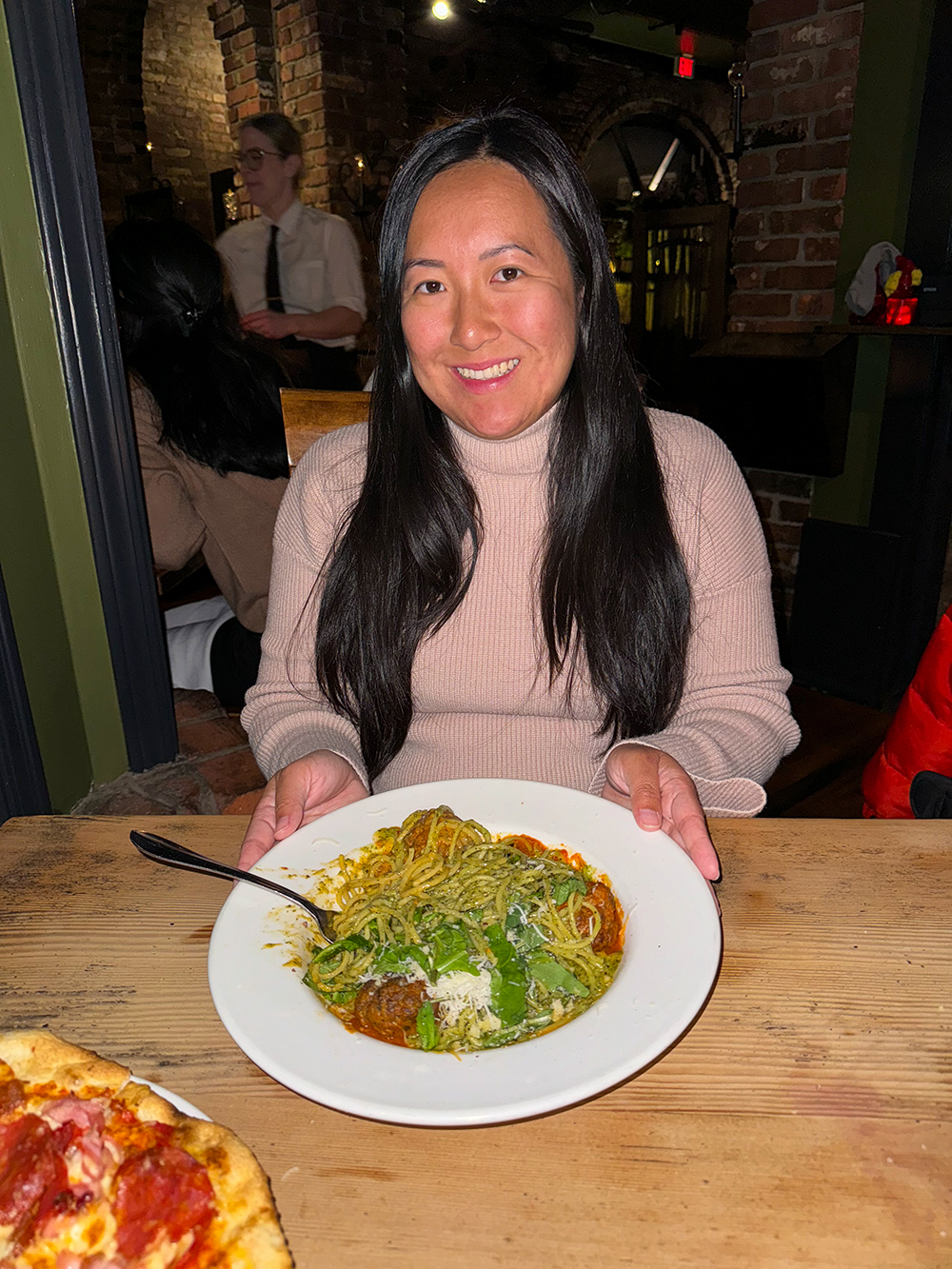 Asian woman sitting at the table with pesto pasta at the Il Terrazzo Ristorante, Victoria, BC Canada
